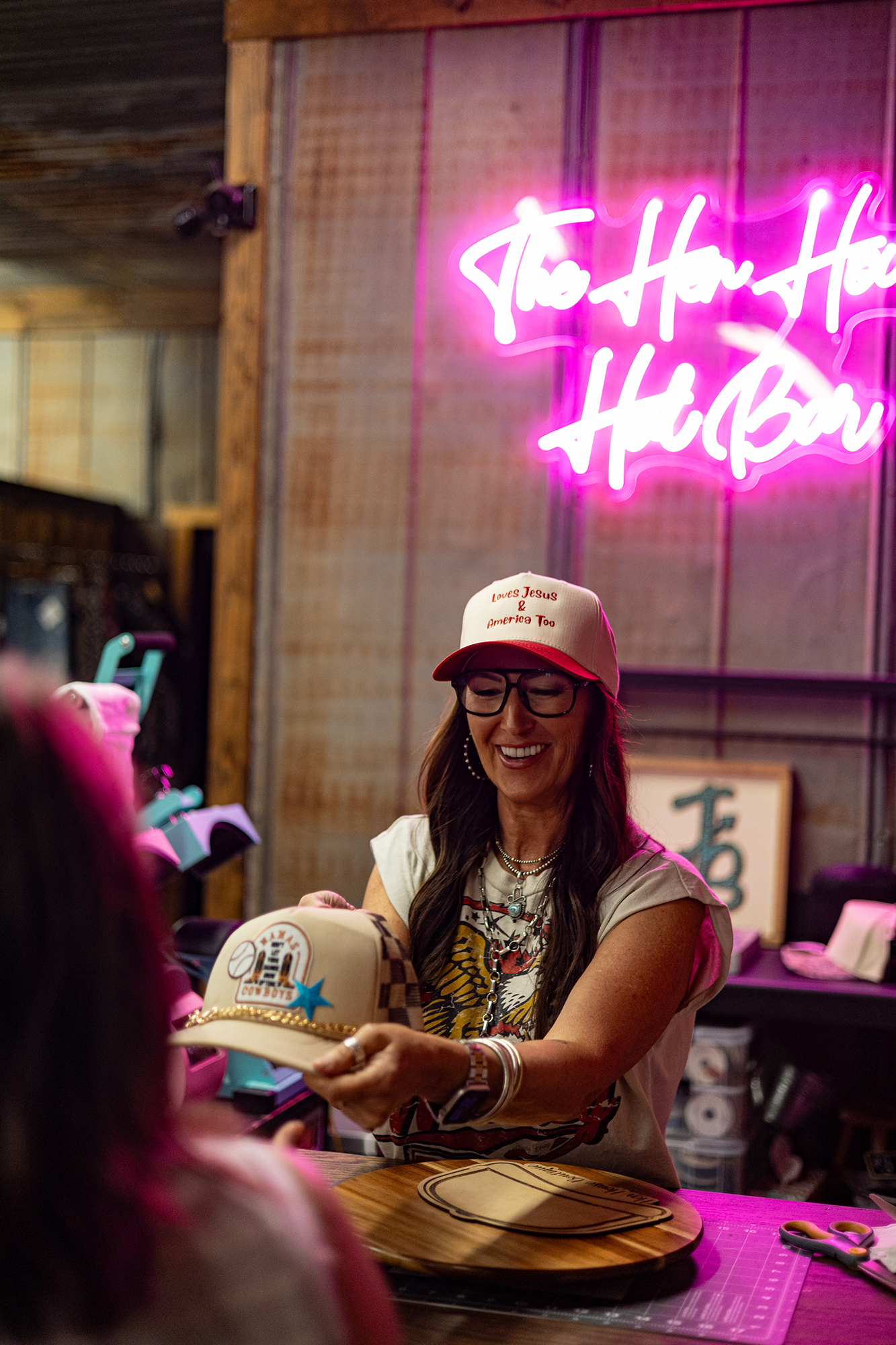Photo of woman giving custom made hat to customer at the Hen House Boutique.