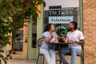 A couple eating gelato at a sidewalk table outside The Turtle Gelateria in downtown Brownwood
