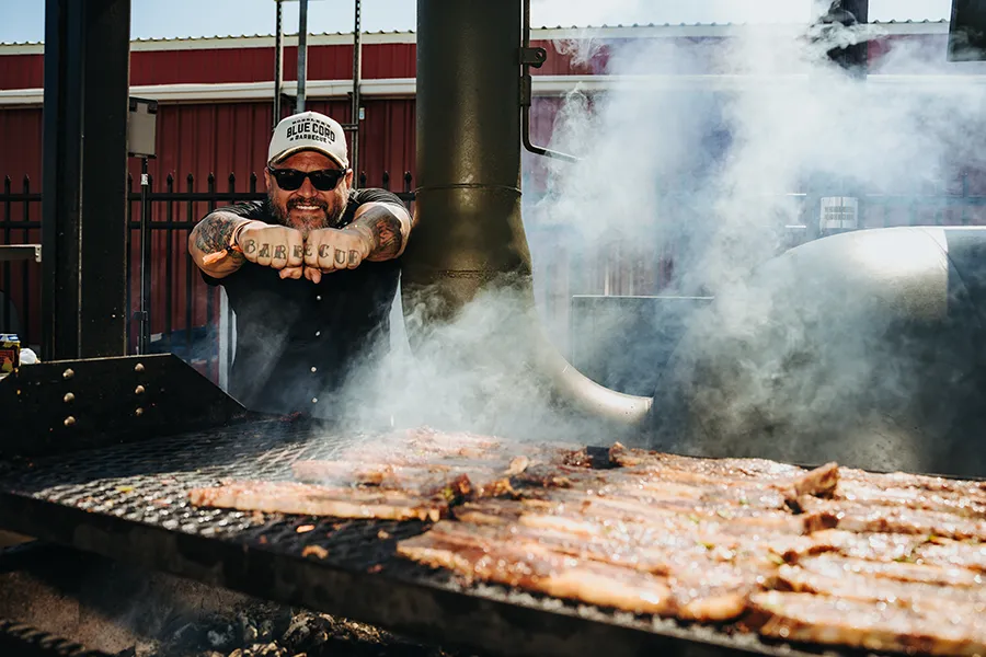 A pitmaster tending a smoking grill full of meat at Feels Like Home Festival