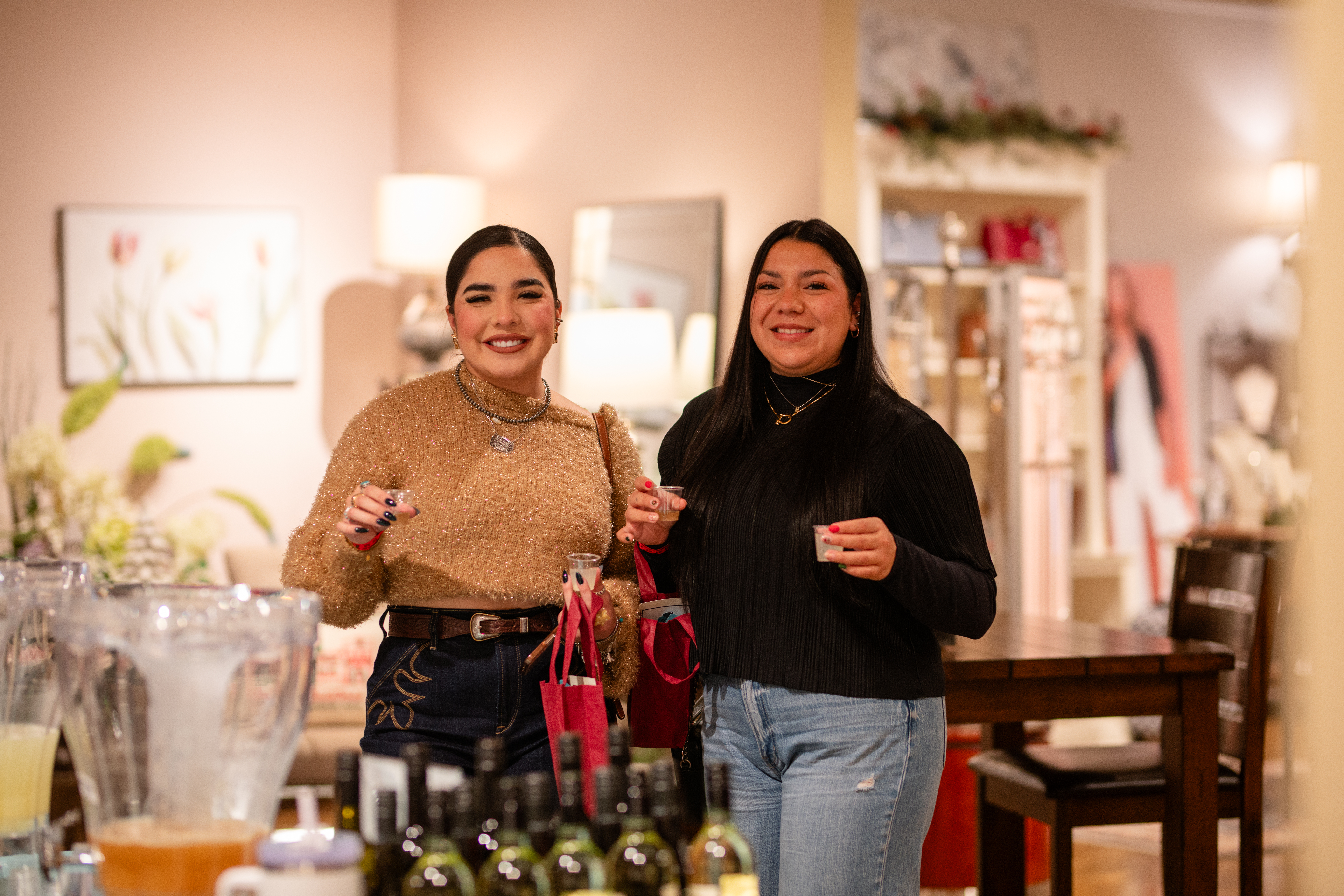 Two women posing for the camera holding wine tastings at the sipping under the stars event.