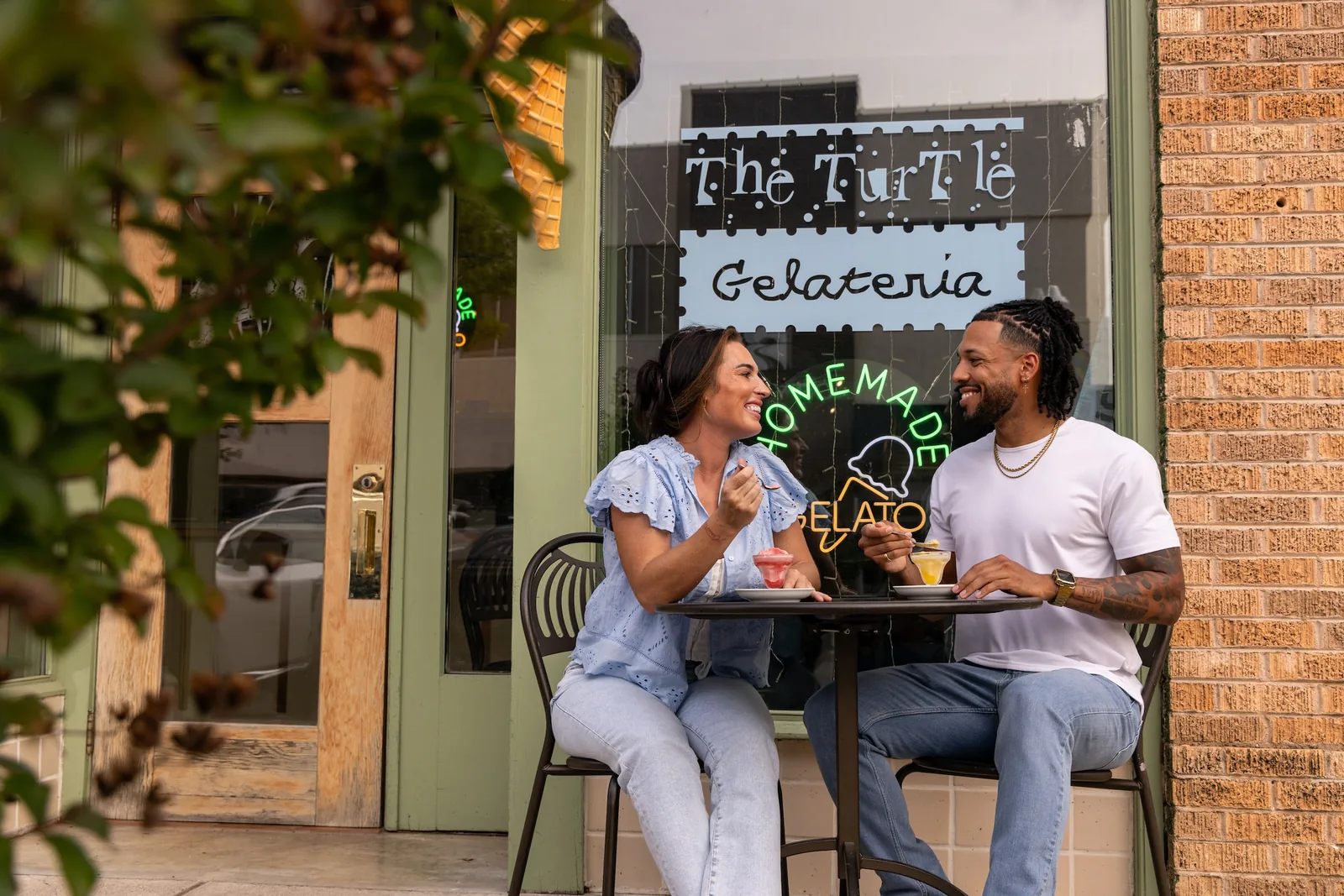 A couple eating gelato at a sidewalk table outside The Turtle Gelateria in downtown Brownwood
