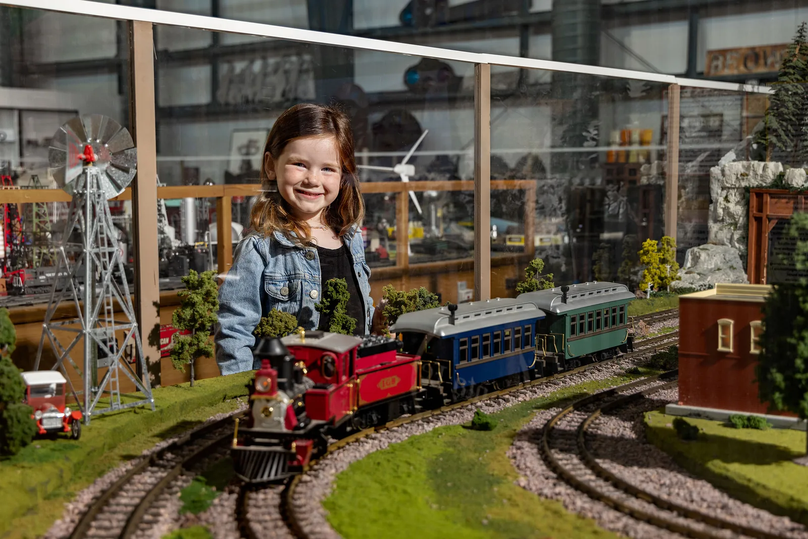 A smiling young girl behind a large model railroad layout at the Martin & Frances Lehnis Railroad Museum