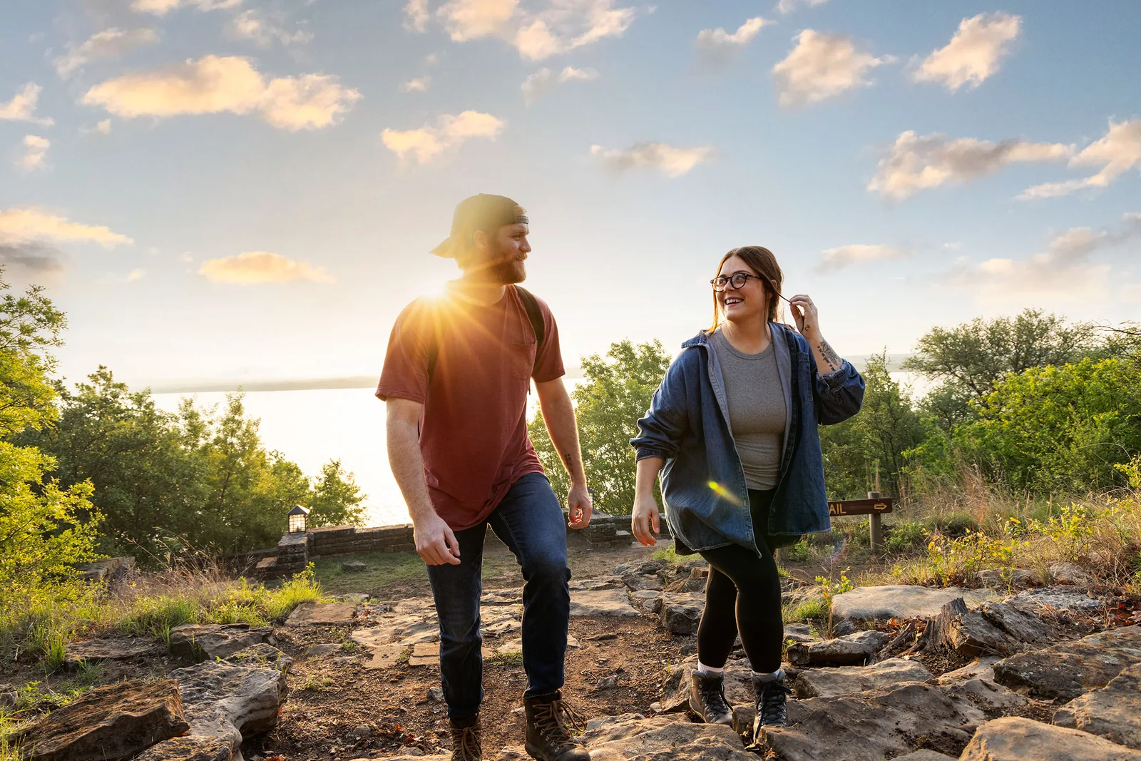 Two hikers on a rocky trail above Lake Brownwood at golden hour