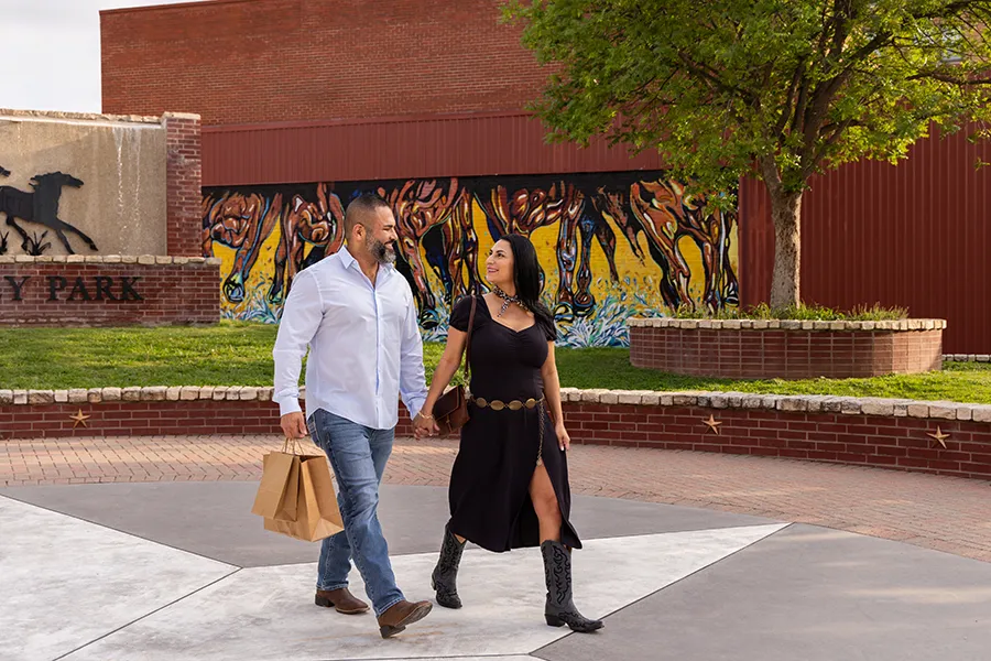 A couple walking with shopping bags past a mural in Downtown Brownwood
